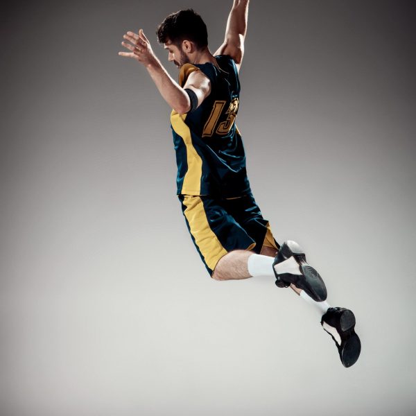 Full length portrait of a basketball player with a ball against gray studio background